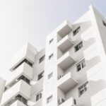 A low angle shot of a facade of a white modern building under a blue clear sky